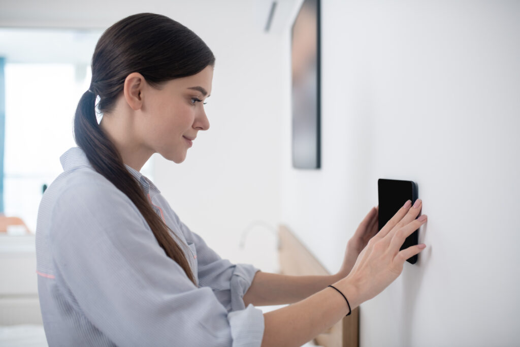 App gratuitas para detectar cámaras ocultas: seguridad fácil (2025) 3 App gratuitas para detectar cámaras ocultas: seguridad fácil (2025) | vista lateral de una hermosa joven concentrada en pegar la tableta la pared