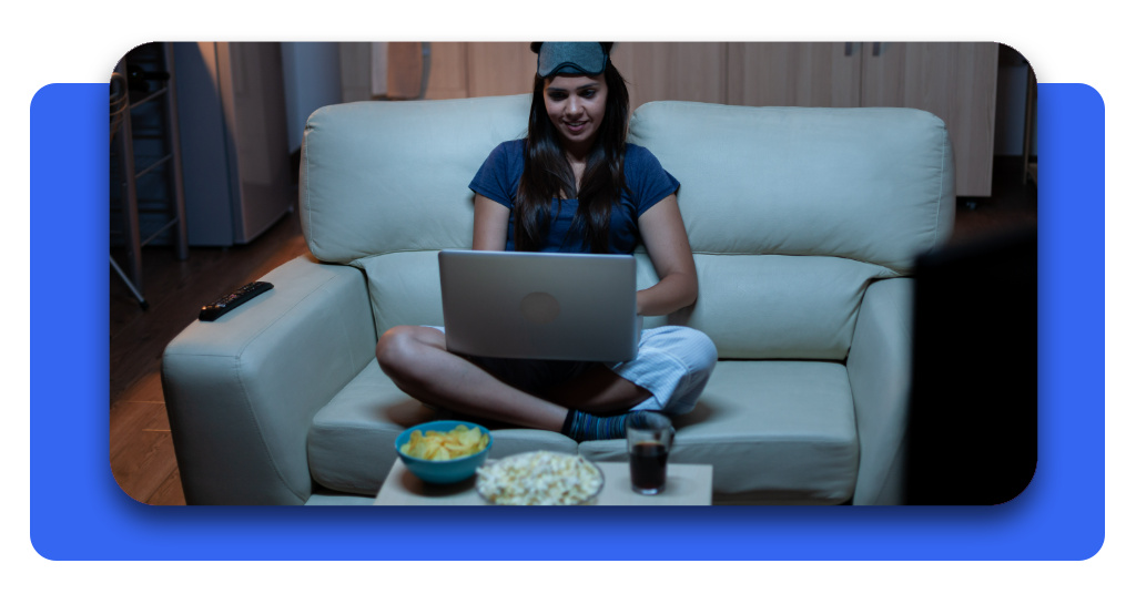Aplicación para ver películas del Oeste gratis ahora mismo 3 Una mujer que lleva puestos los audífonos está acostada en su sofá mientras usa su laptop para ver sus películas favoritas de vaqueros en Pluto TV.