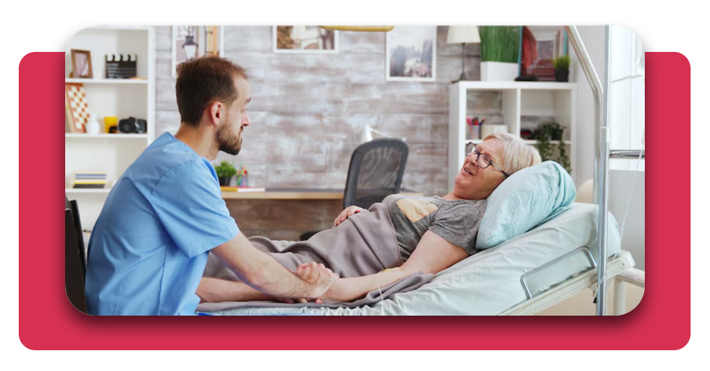 Cuidador masculino hablando con anciana enferma acostada en cama de hospital tomándole la mano