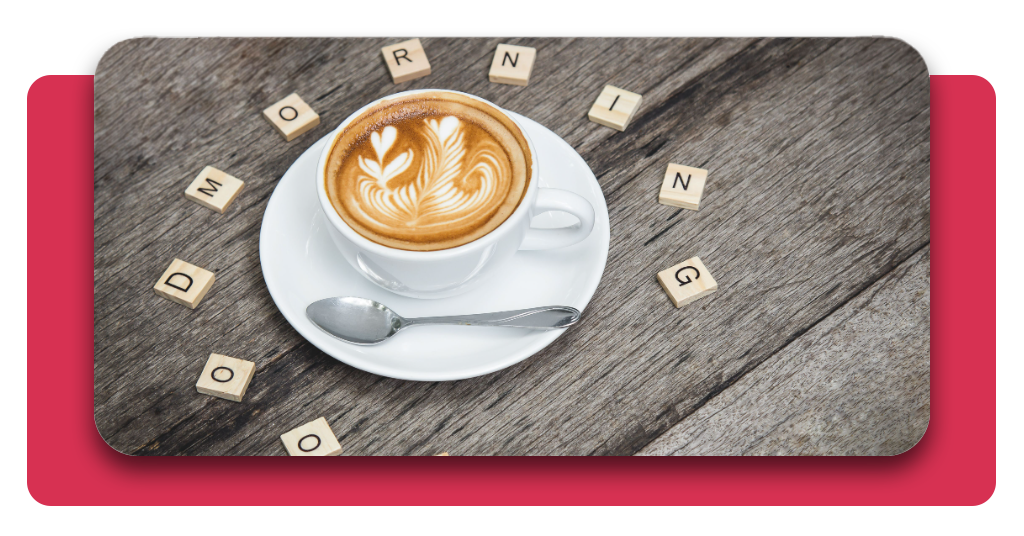 Aplicación con más de 50.000 imágenes de buenos días para usar gratis 3 Una taza de café con arte latte se encuentra en el centro de una mesa de madera, rodeada por letras "GOOD MORNING" o “Buenos Días”.
