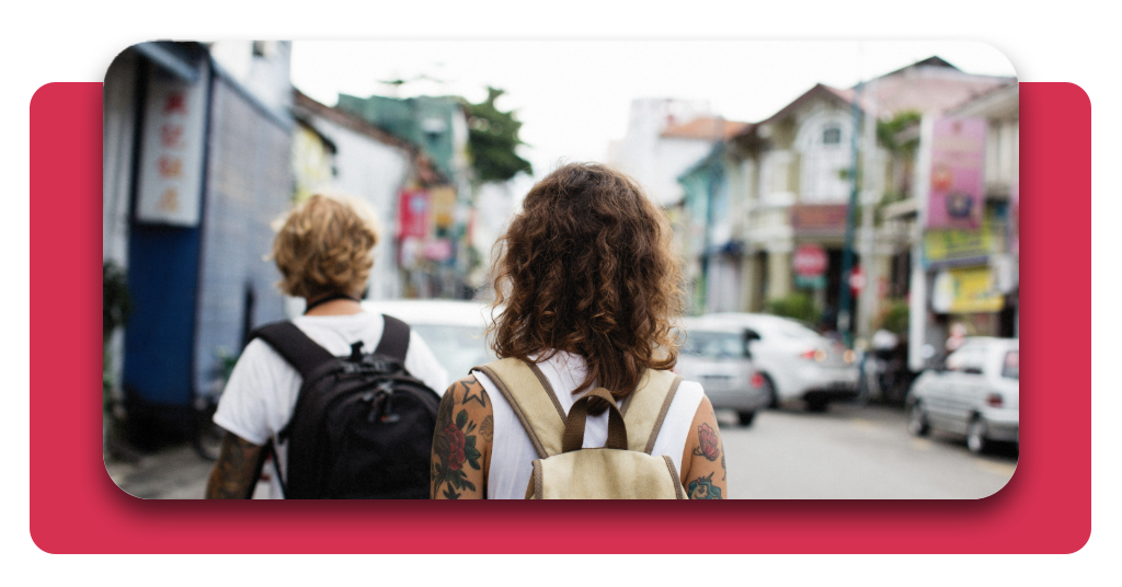 4 mejores apps para viajar que deberías tener en el celular 2 Dos viajeros con sus mochilas se disponen a visitar lugares turísticos para explorar la cultura de una ciudad asiática, mientras recorren una calle concurrida.