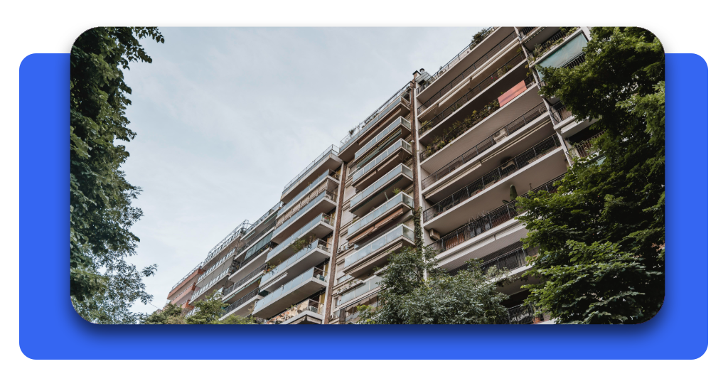 Un edificio residencial urbano rodeado de árboles frondosos. Encontrar una vivienda asequible mejora la estabilidad familiar y el desarrollo de comunidades.