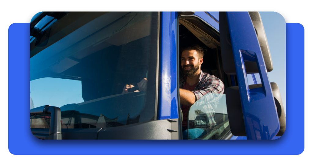 Un camionero sonríe desde su cabina azul. El uso correcto del tacógrafo y respetar los descansos previene los accidentes en la ruta.